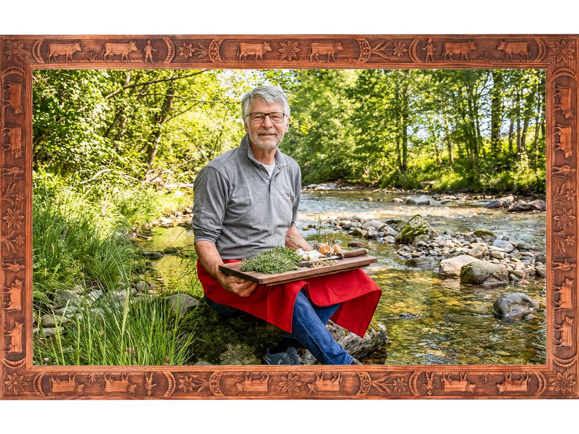 Mann mit frischen Kräutern und Gemüse am Flussufer, umrahmt von einem geschnitzten Holzrahmen.