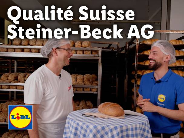 Deux hommes souriants dans une boulangerie avec du pain frais et le logo Lidl.