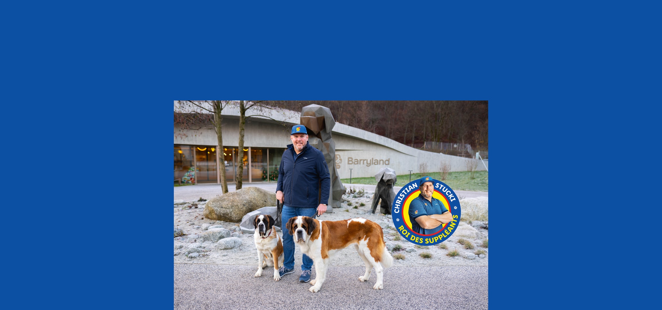 Un homme avec deux chiens Saint-Bernard devant le bâtiment Barryland.