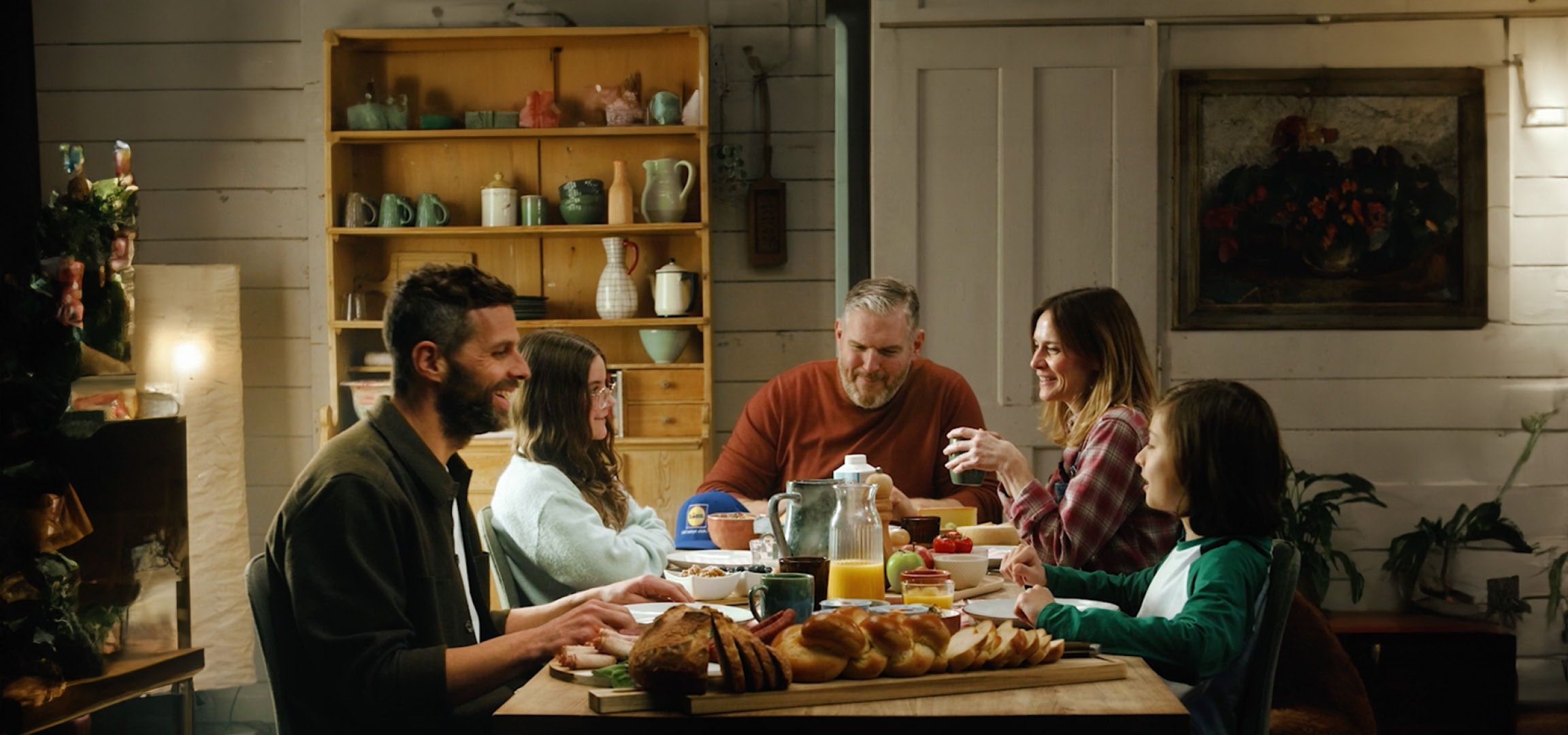 Famille et amis partageant un repas avec du pain, des fruits et du jus d'orange.