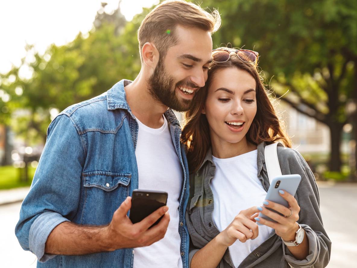 Couple utilisant des smartphones dehors.