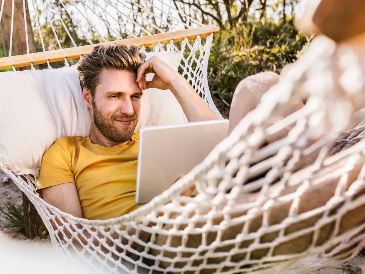 Homme dans un hamac utilisant une tablette.