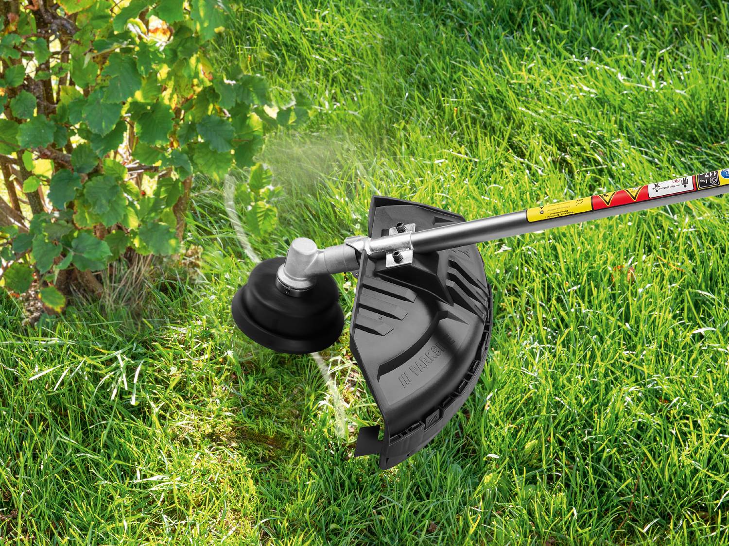 Decespugliatore che taglia l'erba vicino a un cespuglio