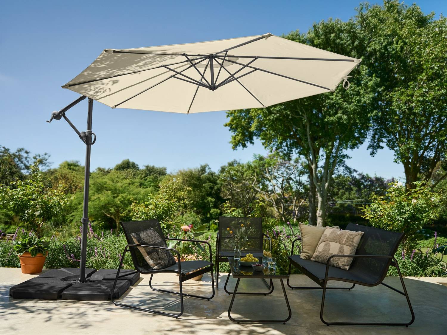 Gartenlounge-Set mit Ampelschirm, zwei Sesseln und einem Couchtisch.