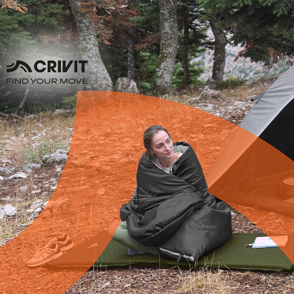 Frau in Schlafsack auf Isomatte, mit Zelt und Turnschuhen beim Camping.