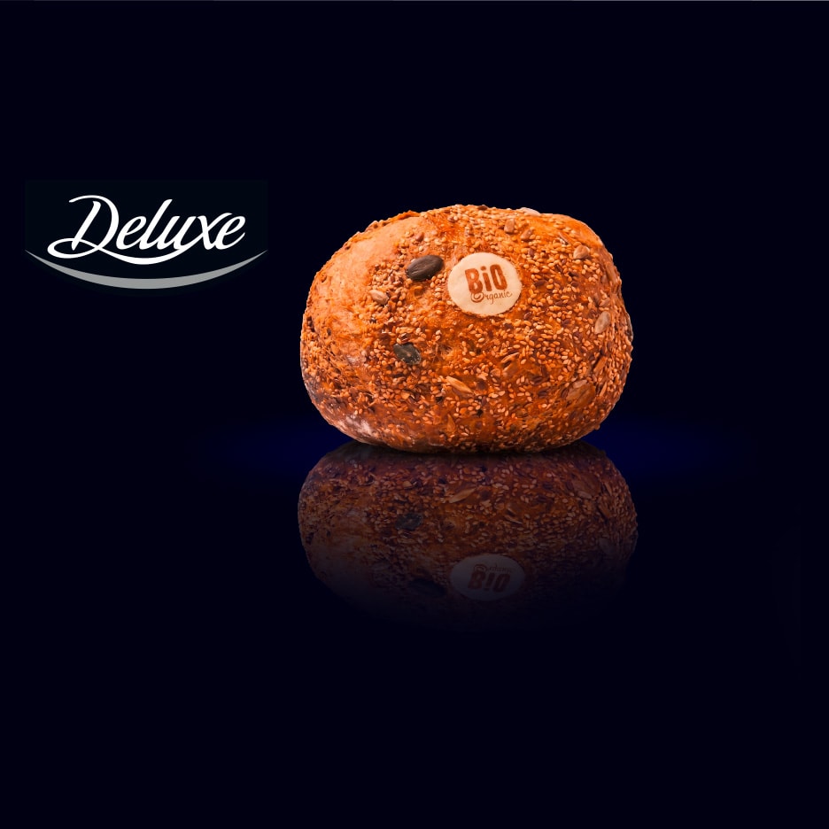 Ein Bio-Brötchen mit Samen und Körnern auf dunklem Hintergrund mit Reflexion.
