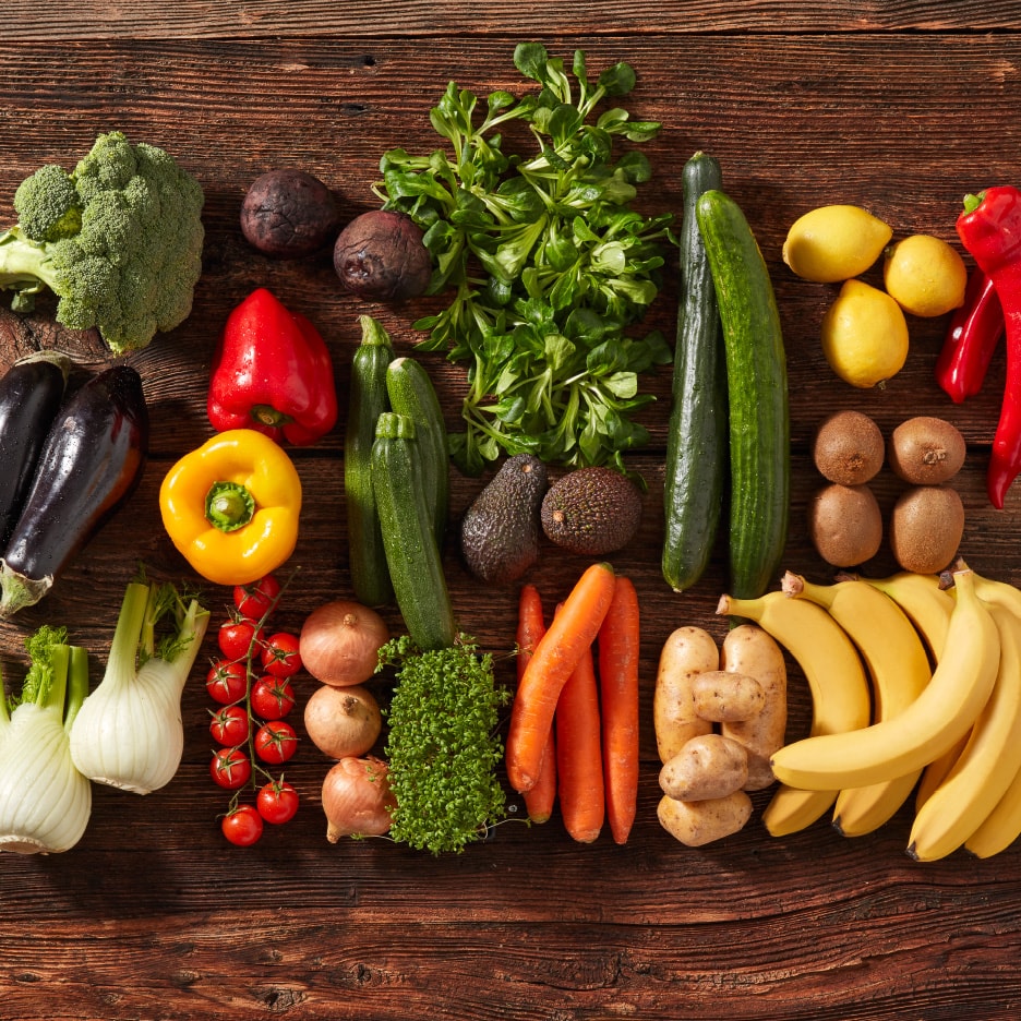 Eine Vielfalt an frischem Obst und Gemüse auf einem Holztisch arrangiert.