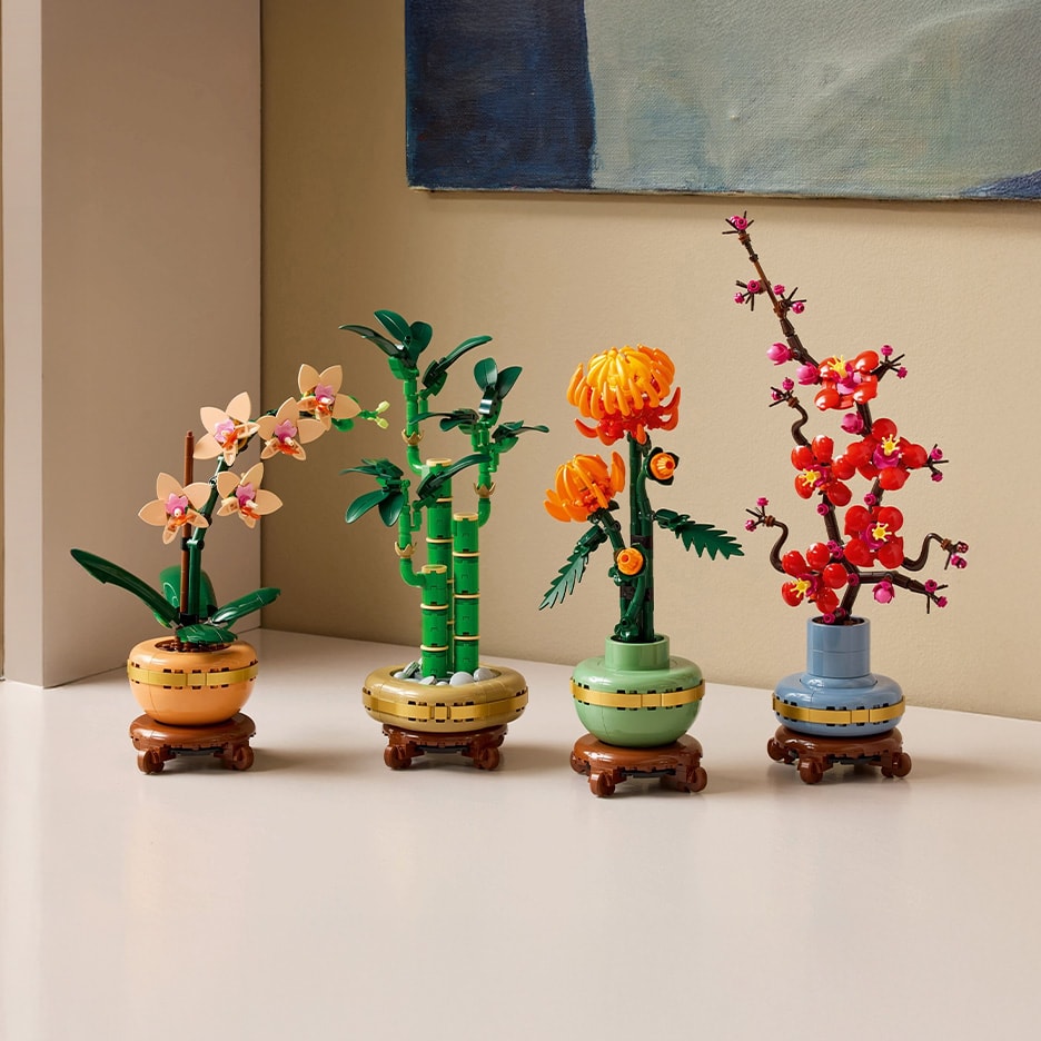 Vier Zierpflanzen aus Bausteinen, darunter eine Orchidee, Bambus, Chrysanthemen und Pflaumenblüten.