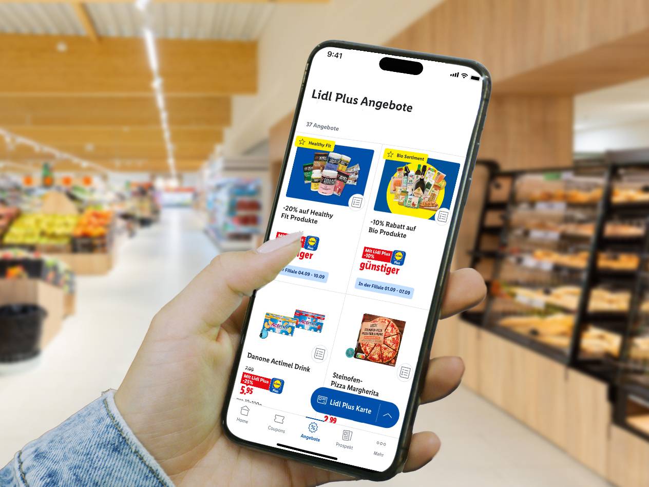 Hand hält Smartphone mit Lidl Plus App, die Angebote für gesunde Produkte, Bio-Sortiment, Actimel und Pizza anzeigt, im Supermarkt.