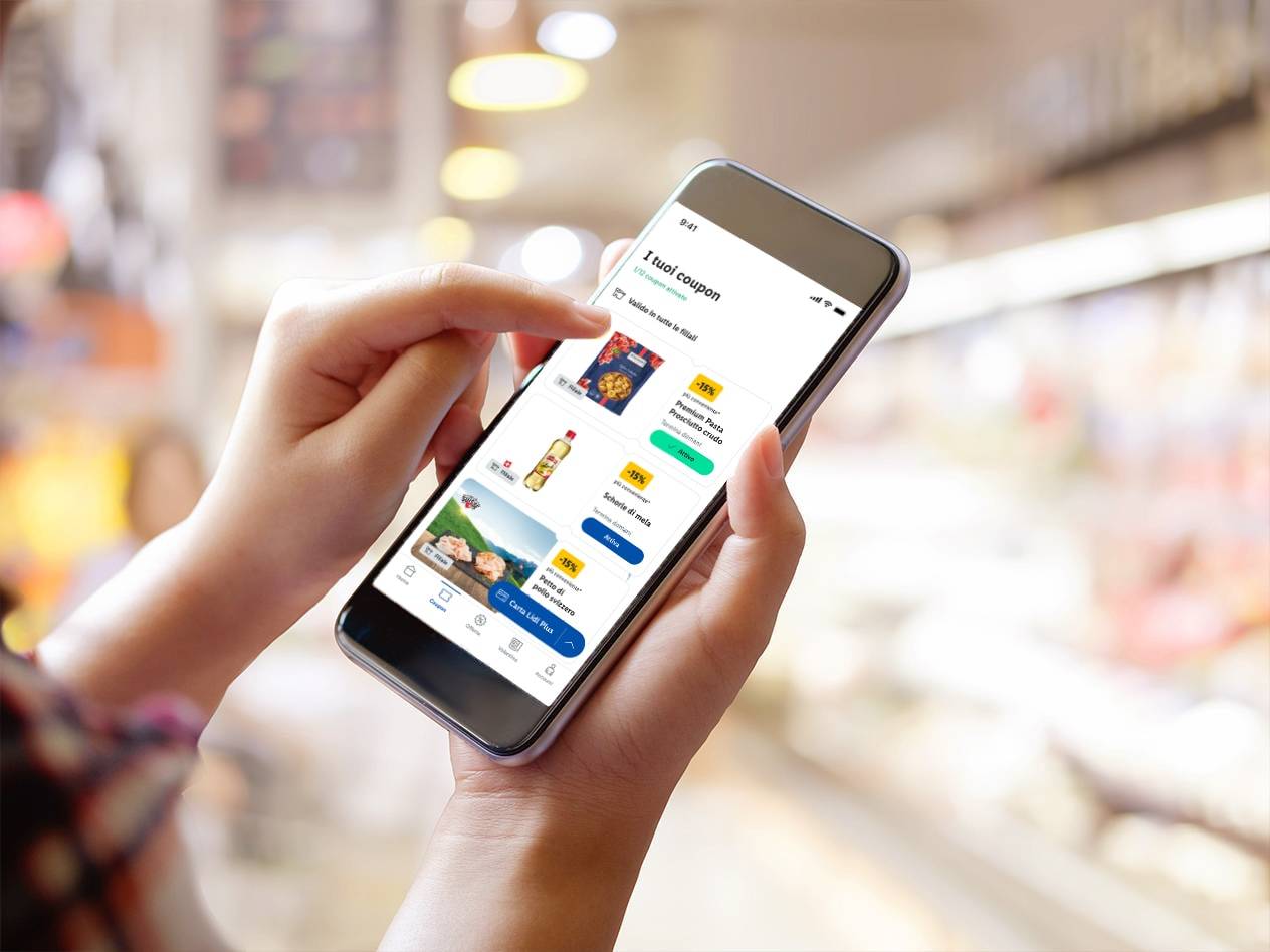 Una persona usa l'app Lidl Plus per visualizzare coupon su pasta, olio e pollo.