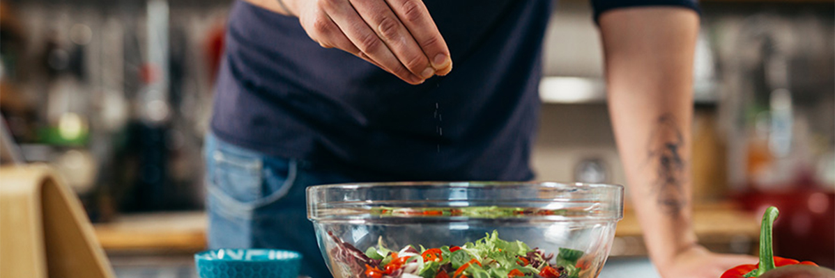 Uomo che condisce un'insalata.