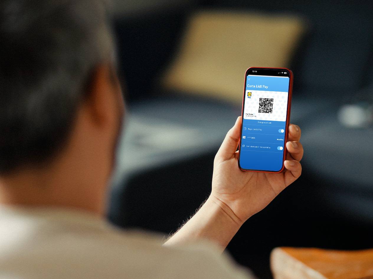 Un uomo tiene uno smartphone che mostra una carta fedeltà digitale con un codice QR.