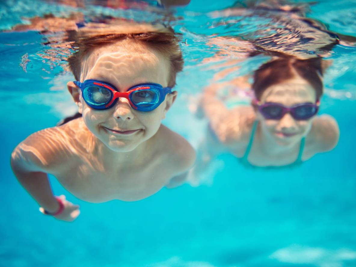 Kinder mit Schwimmbrillen unter Wasser.