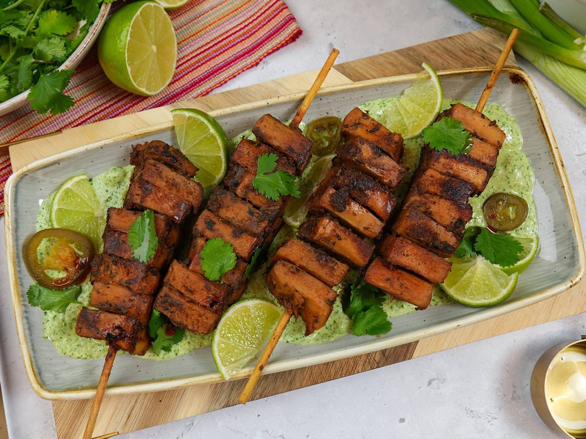 Gegrillte Tofuspieße mit Limetten, Koriander und Jalapeños auf einer grünen Soße.