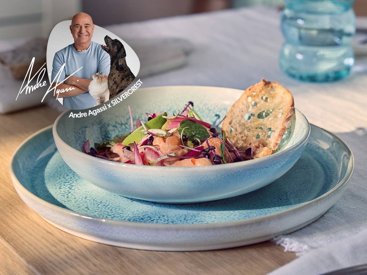 Eine Schale Lachs-Salat mit geröstetem Brot auf einem blauen Teller, mit einem Porträt von Andre Agassi.