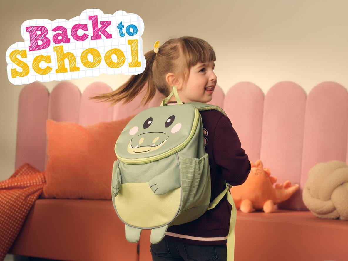 Ein kleines Mädchen mit einem Krokodil-Rucksack, bereit für die Schule.